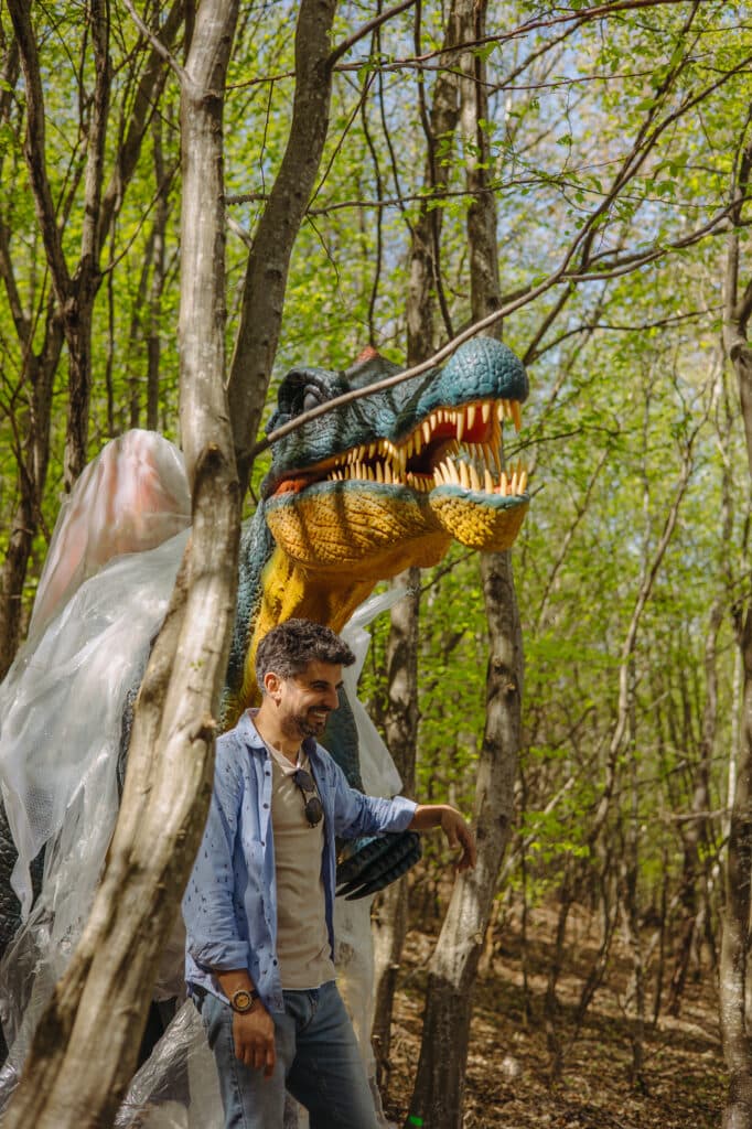 Vizitator lângă un dinozaur în pădure. Imagine de arhivă.